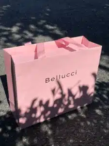 Angled view of Bellucci luxury pink shopping bag showing ribbon handles and sturdy side gussets