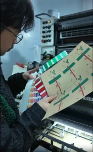 Technician compares printed sheet with Pantone swatch book to control color differences on an offset press